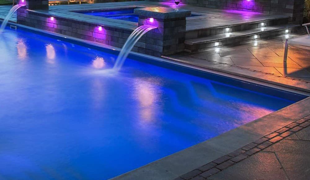 Landscape and hardscape lighting around a pool at dusk
